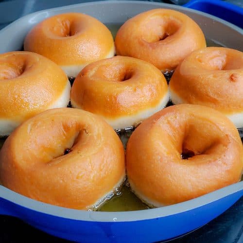 Doughnuts frying in hot oil in a blue pan